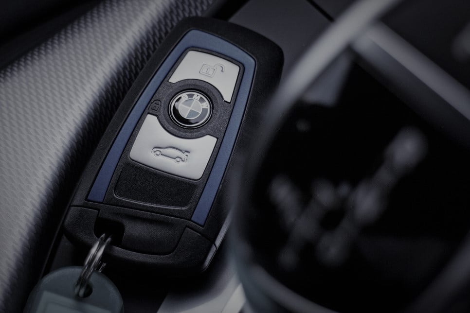 BMW key in black and blue laying next to carbon fibre trim in the car interior.
